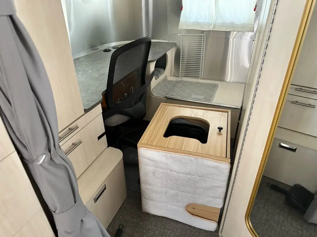 The cat's litter box sits on its back, with the toppled litter container in disarray inside the box with litter everywhere
