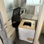 The cat's litter box sits on its back, with the toppled litter container in disarray inside the box with litter everywhere