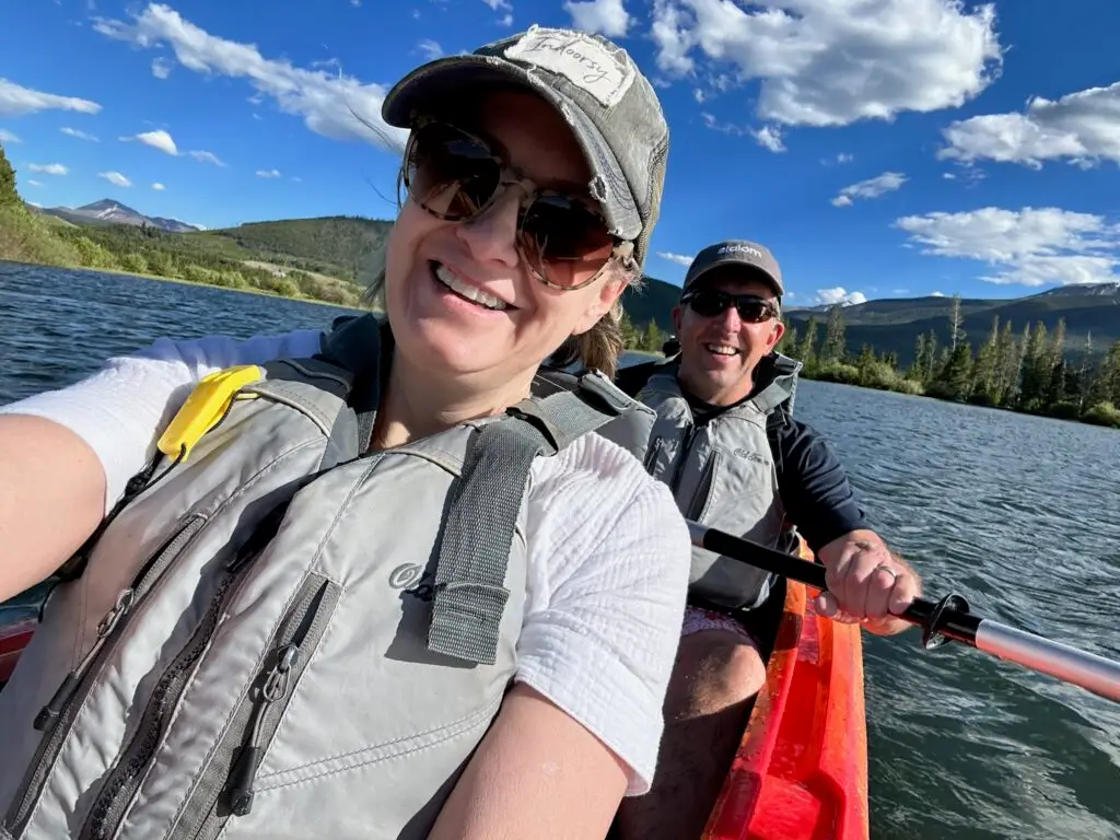 Anne takes a selfie in the kayak with Bill in the background