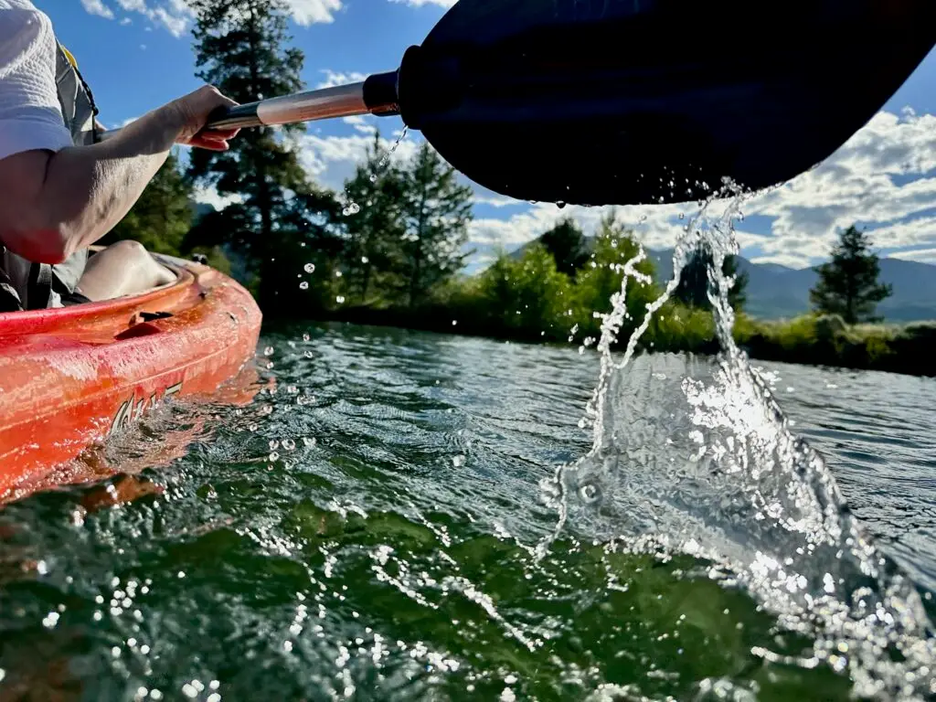 Water splashes along the oar as it lifts off the surface and moves forward to take the next stroke in the kayak at Dillon Reservoir