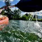 Water splashes along the oar as it lifts off the surface and moves forward to take the next stroke in the kayak at Dillon Reservoir