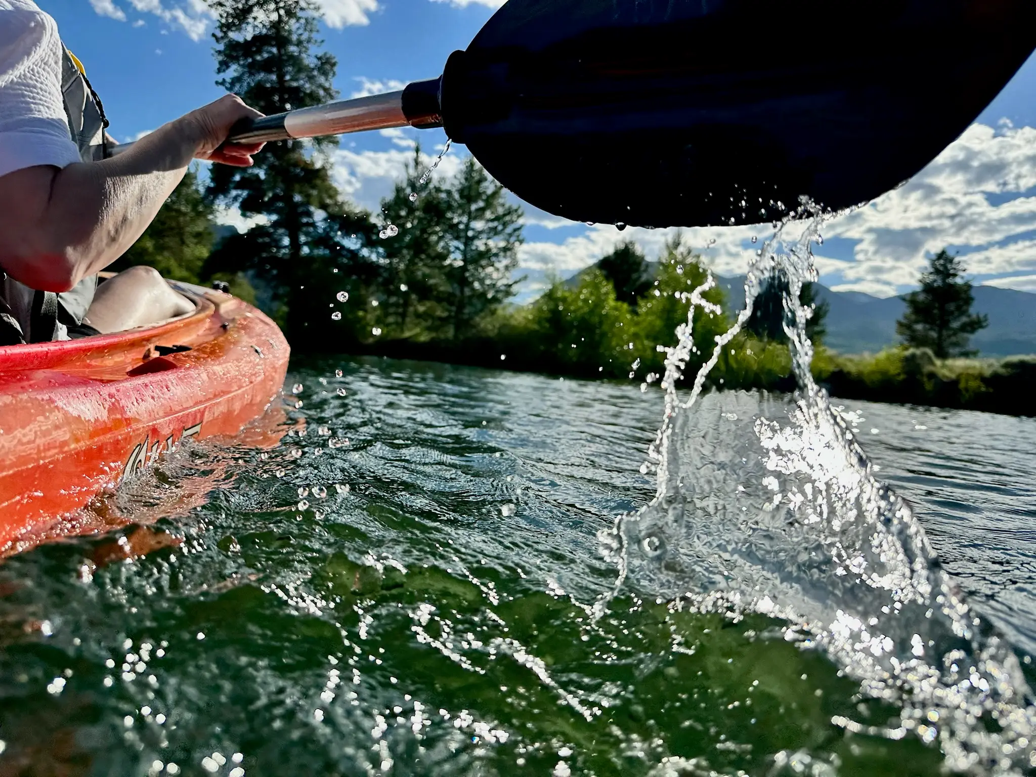 Water splashes along the oar as it lifts off the surface and moves forward to take the next stroke in the kayak at Dillon Reservoir