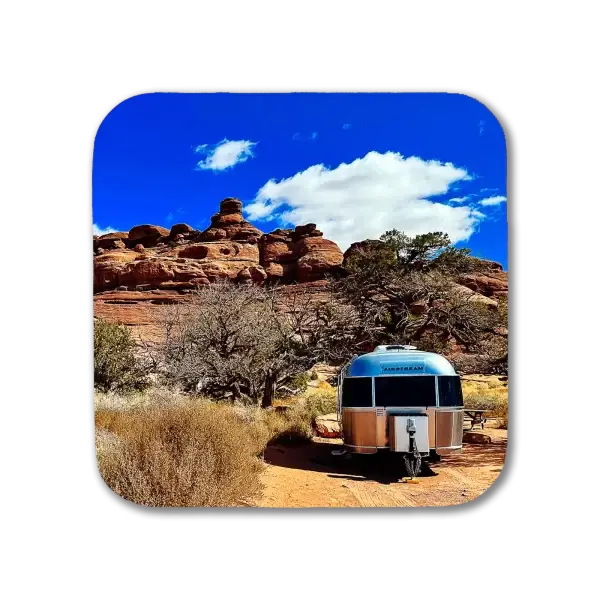 Coaster featuring an Airstream against a backdrop of red rocks in Canyonlands National Park