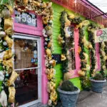 A neon-green painted business along Magazine Street is decorated with gold and white holiday bulbs and garland