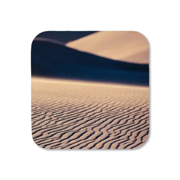 Whispers of sand progress in irregular lines down a hill as the wind blows them around, artwork for a coaster