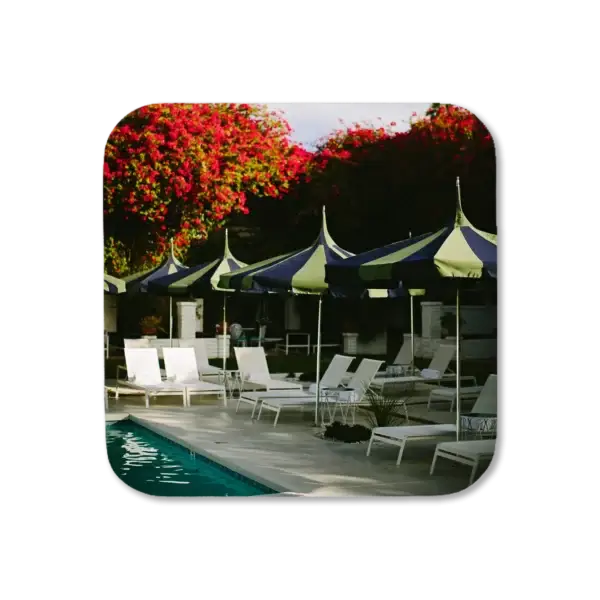 Scenes from around a secluded pool with umbrellas and white lounge chairs surrounding, artwork for a coaster