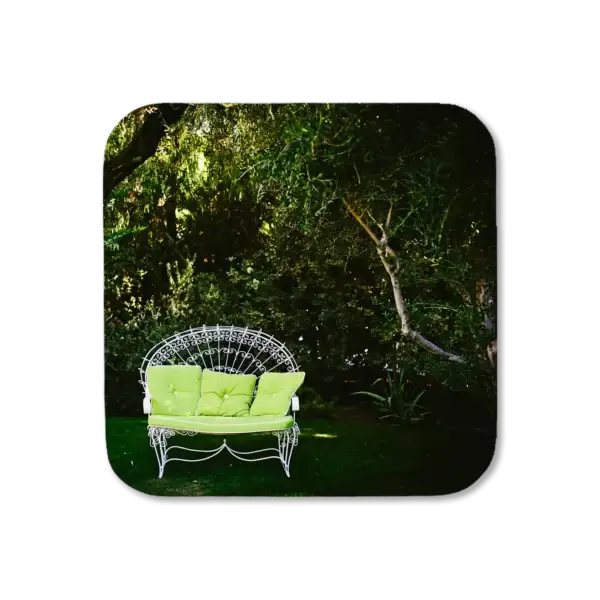 Loveseat set among the grass outside with white ornate framing, artwork for a coaster