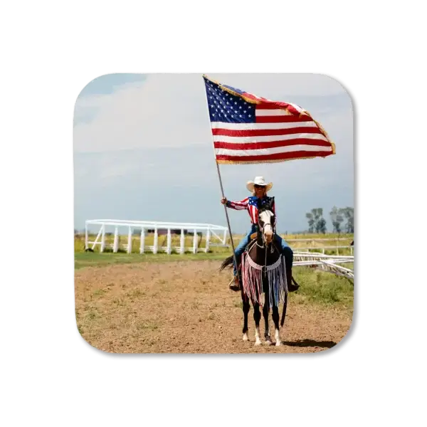 A cowgirl stands outside the rodeo area, holding an American flag flying in the wind, waiting for the last event to signal the close to the rodeo, artwork for a coaster