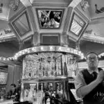 Selfie of Anne & Bill in the Carousel Bar mirrors while a bartender shakes a cocktail in the Hotel Monteleone