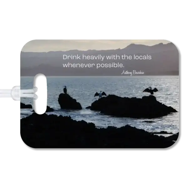 New Zealand luggage tag Premium luggage tag featuring New Zealand sea birds sunning themselves on coastal rocks on a bay. Superimposed quote says Drink heavily with the locals whenever possible, by Anthony Bourdain